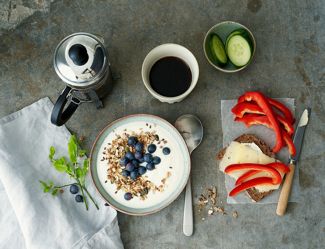 Frühstück mit Joghurtmüsli, Kaffee und Käsebrot mit Paprika