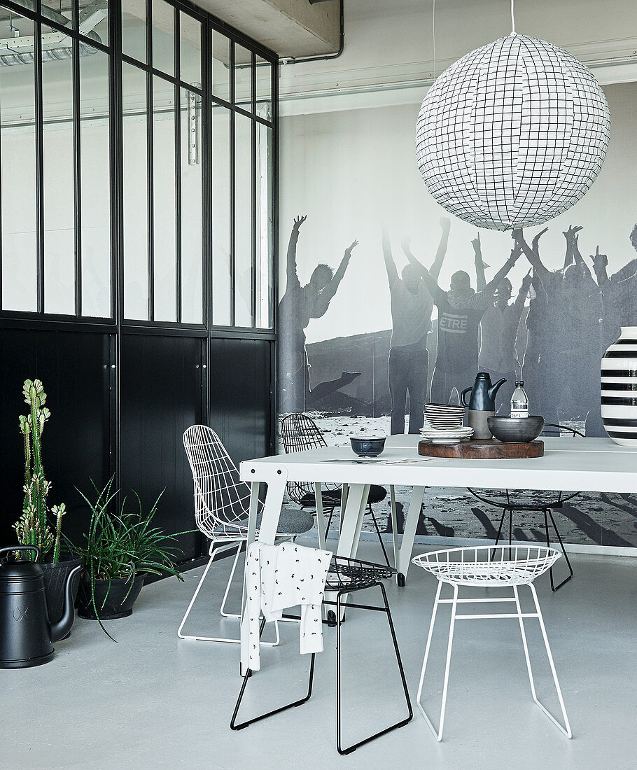 White metal table and wire chairs in black-and-white dining area of loft apartment