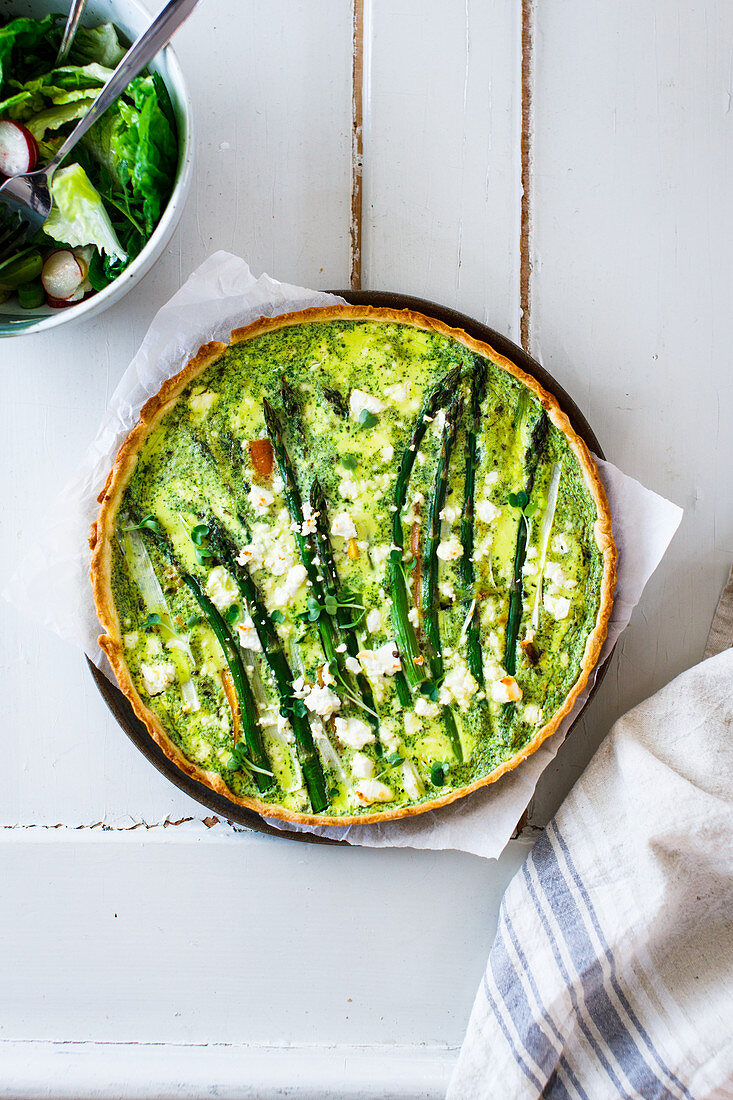Asparagus tart on a brown board, with negative space