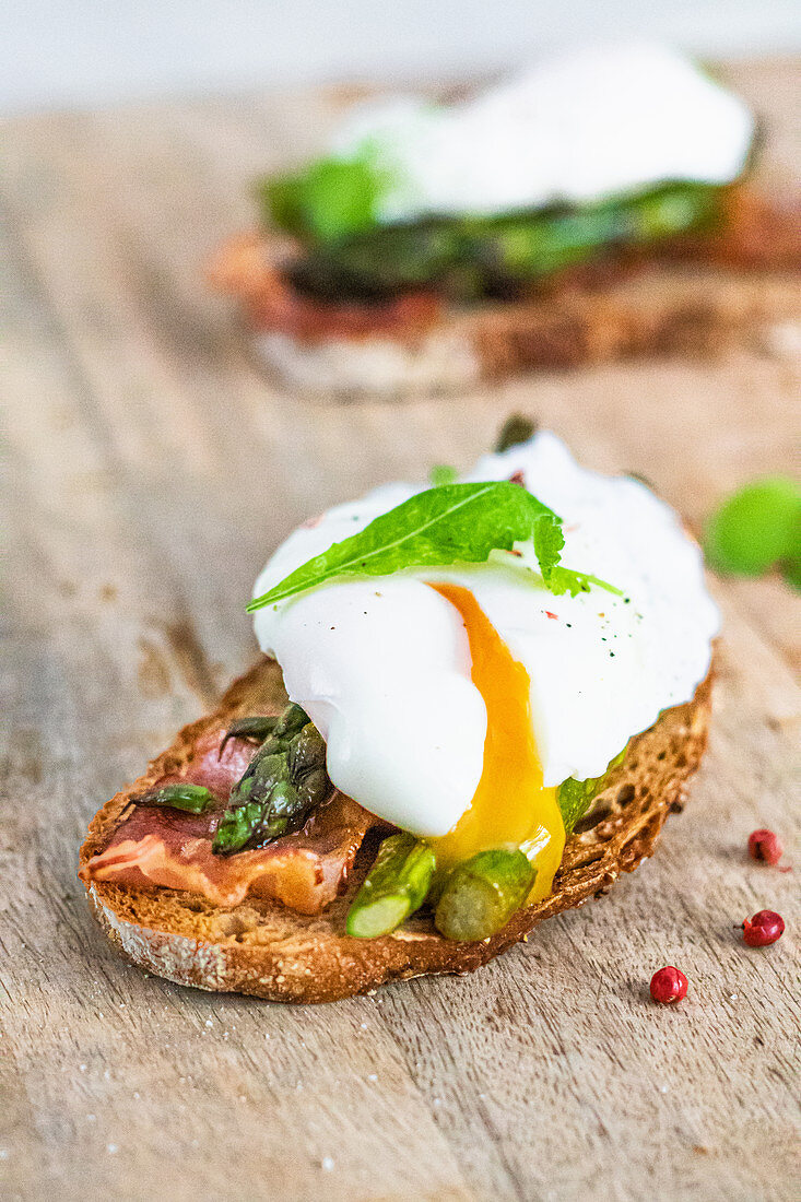 Toasts with green asparagus bacon and poached egg with pouring yolk