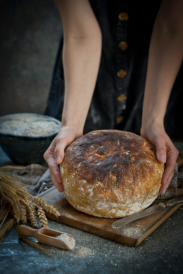 Frau hält frisch gebackenes Sauerteigbrot