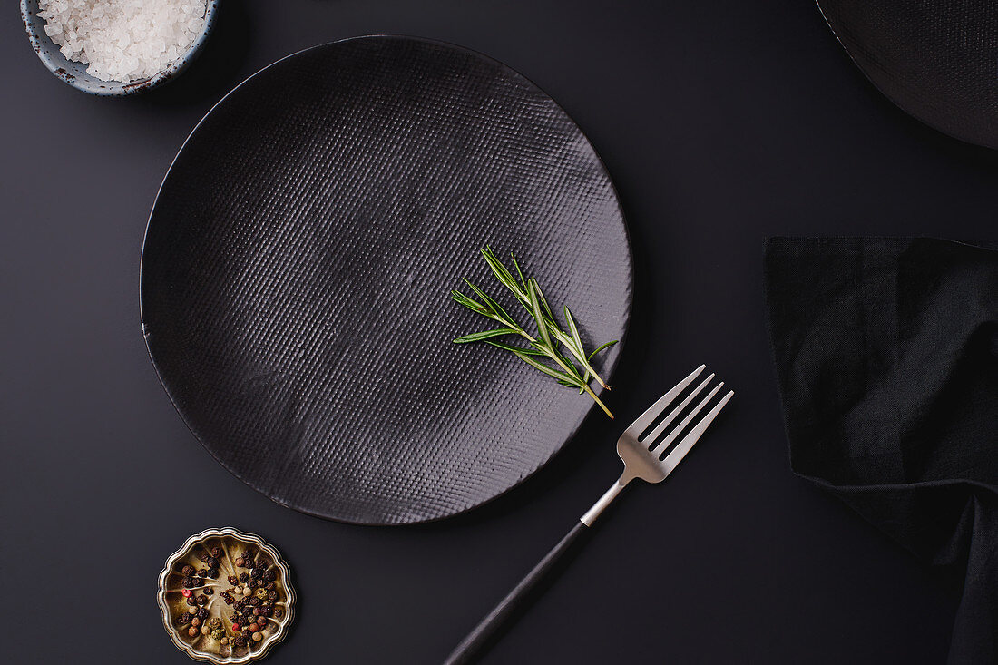 Black dinner setting - empty plates on dark background