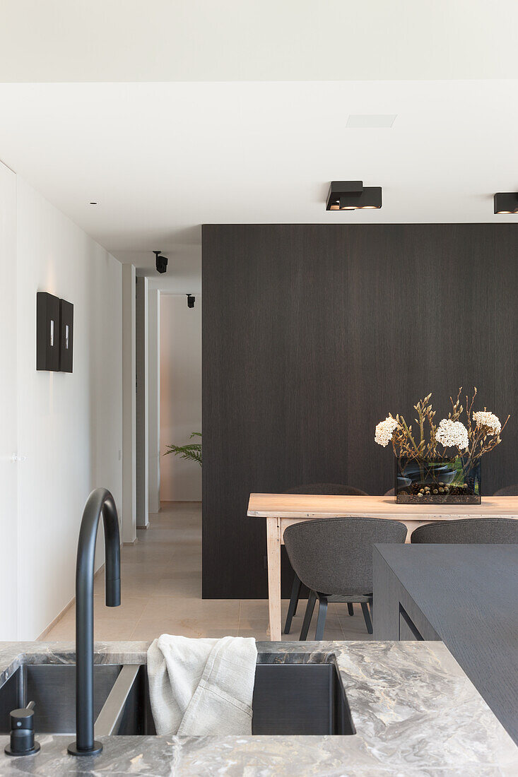 Kitchen with marble worktop and dining area with dark wooden wall