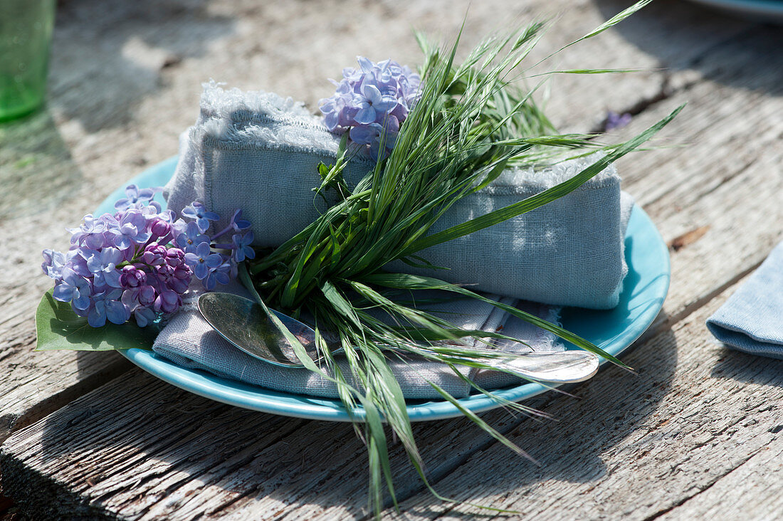 Wreath made of grass as a napkin ring, decorated with lilac blossoms
