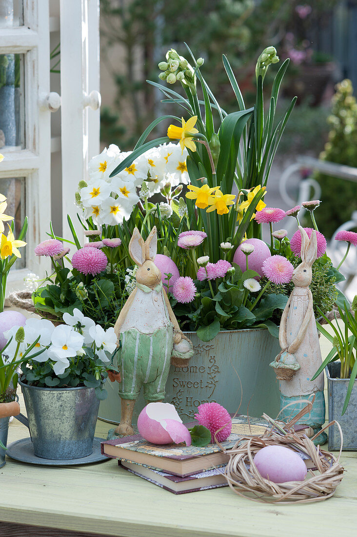Daisy, daffodils, primroses and grape hyacinths in a tin bowl, horned violets in zinc cups, Easter eggs and Easter bunnies