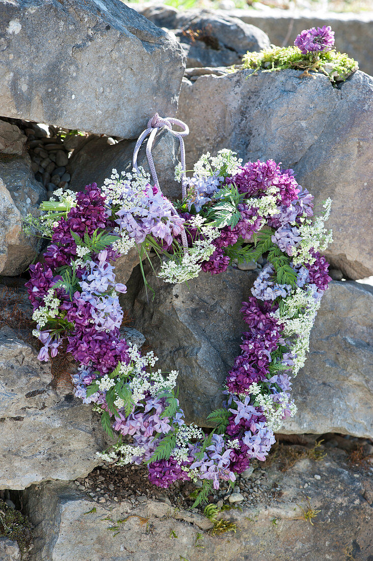 Heart of lilac blossoms and hemlock on dry stone wall