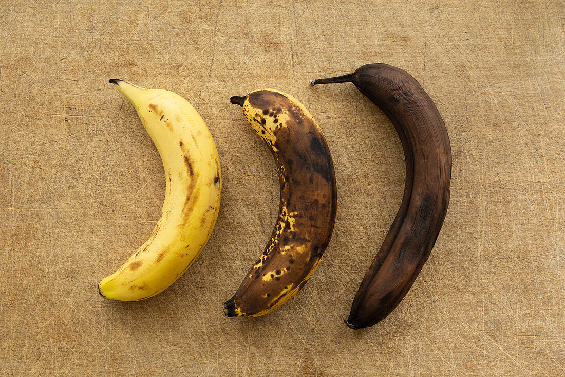 Three bananas in different stages of ripening