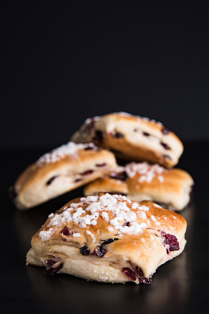 Milk buns with cranberries and nib sugar against a black background