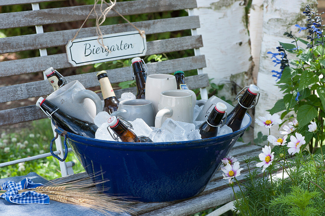 Bierkrüge und Bierflaschen gekühlt in Schüssel mit Eiswürfeln