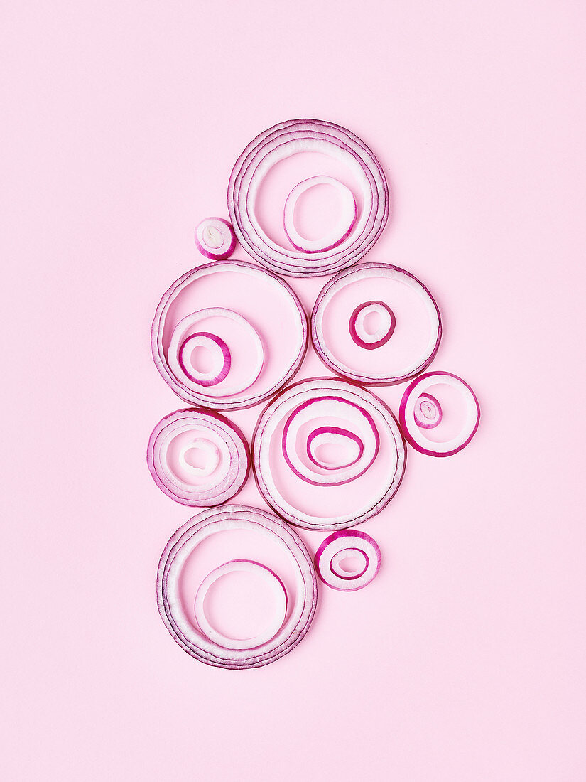 Several red onion rings on a pink paper background