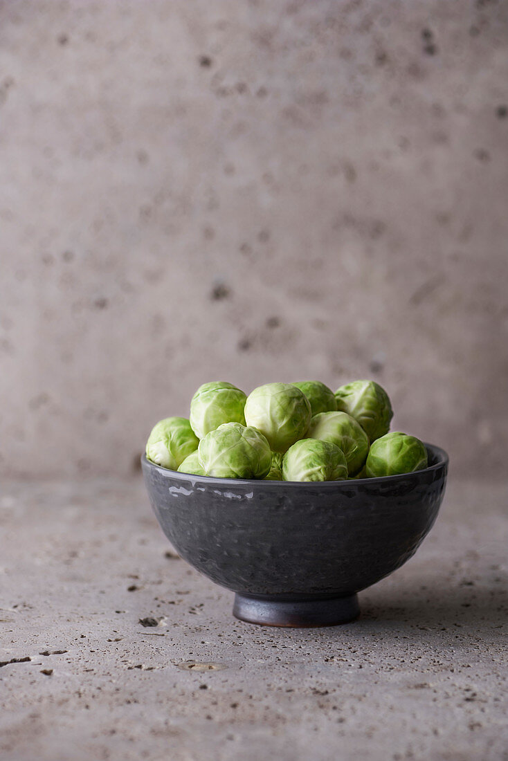 Brussels sprouts in a gray bowl on a stone background