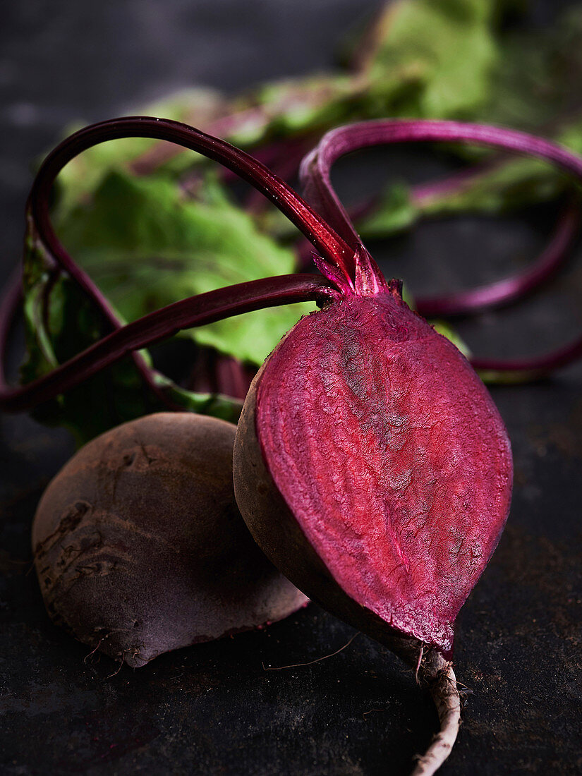 Sliced beetroot with leaves on a black background