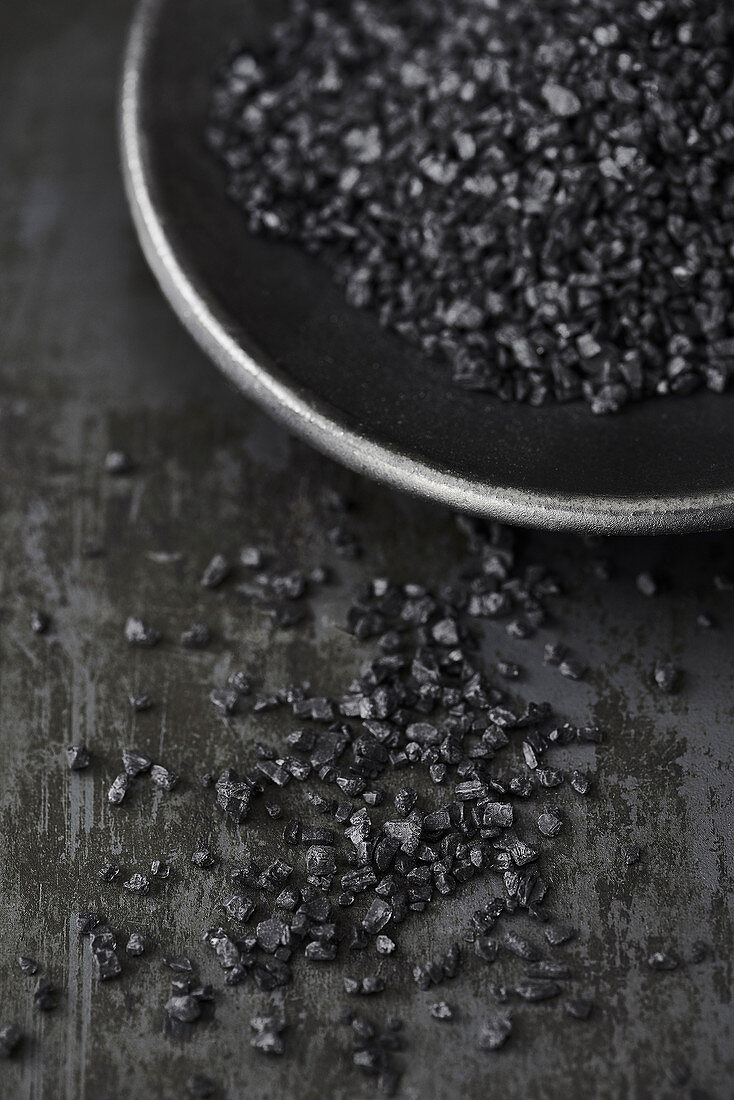 Black salt in a black bowl on a metal surface