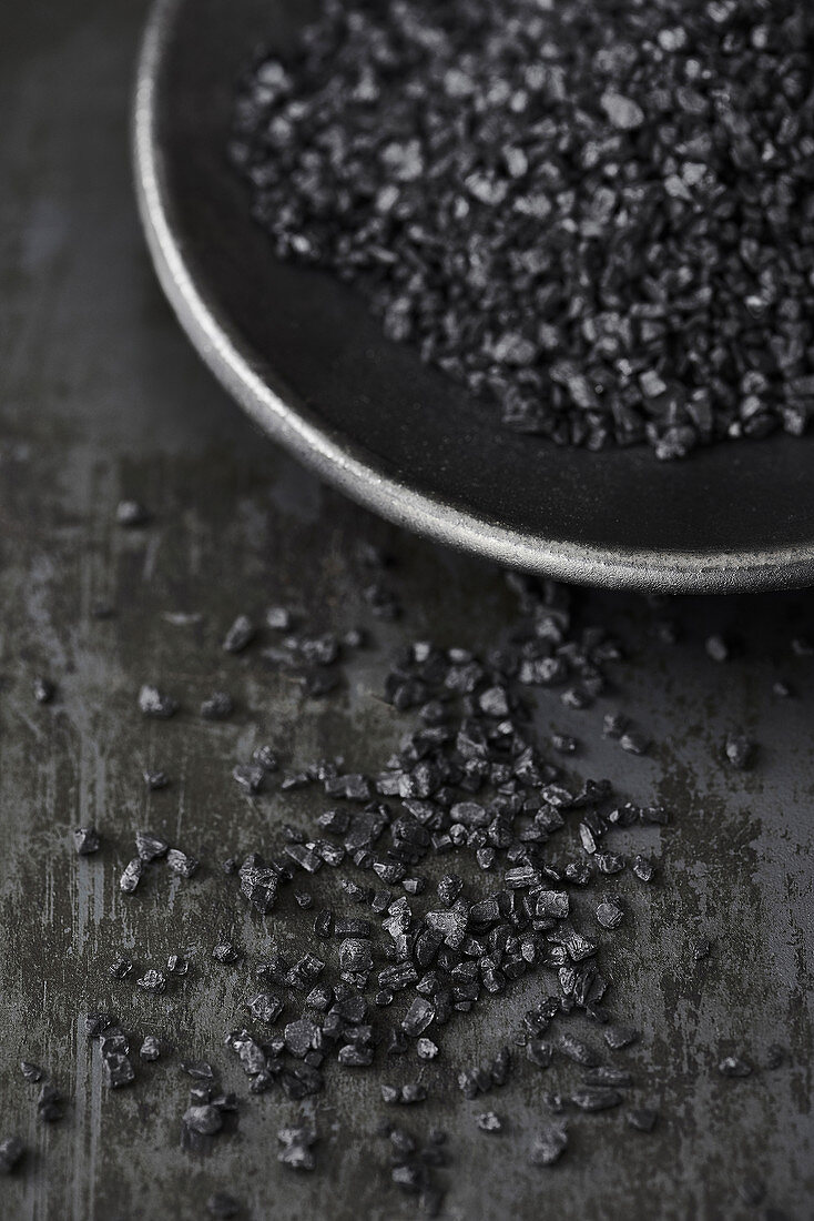 Schwarzes Salz in schwarzer Schale auf Metalluntergrund