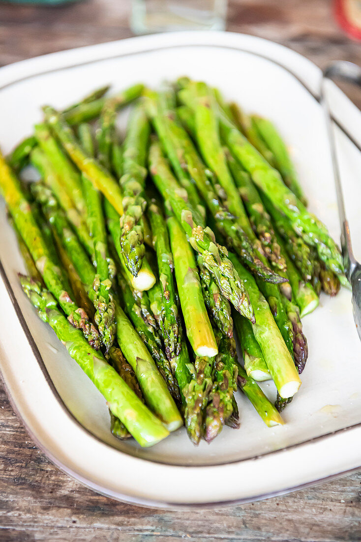 Tray of roasted asparagus on wooden table