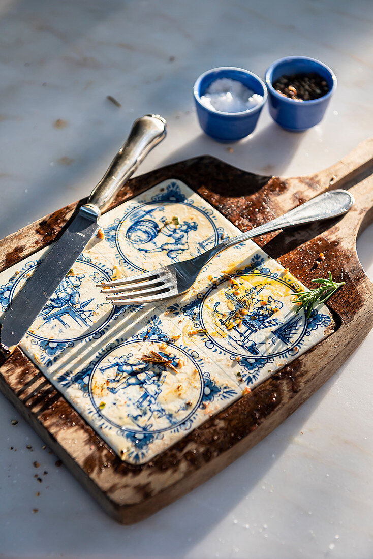 Ceramic and wood board on marble table with remaining oil and cutlery after eating a steak