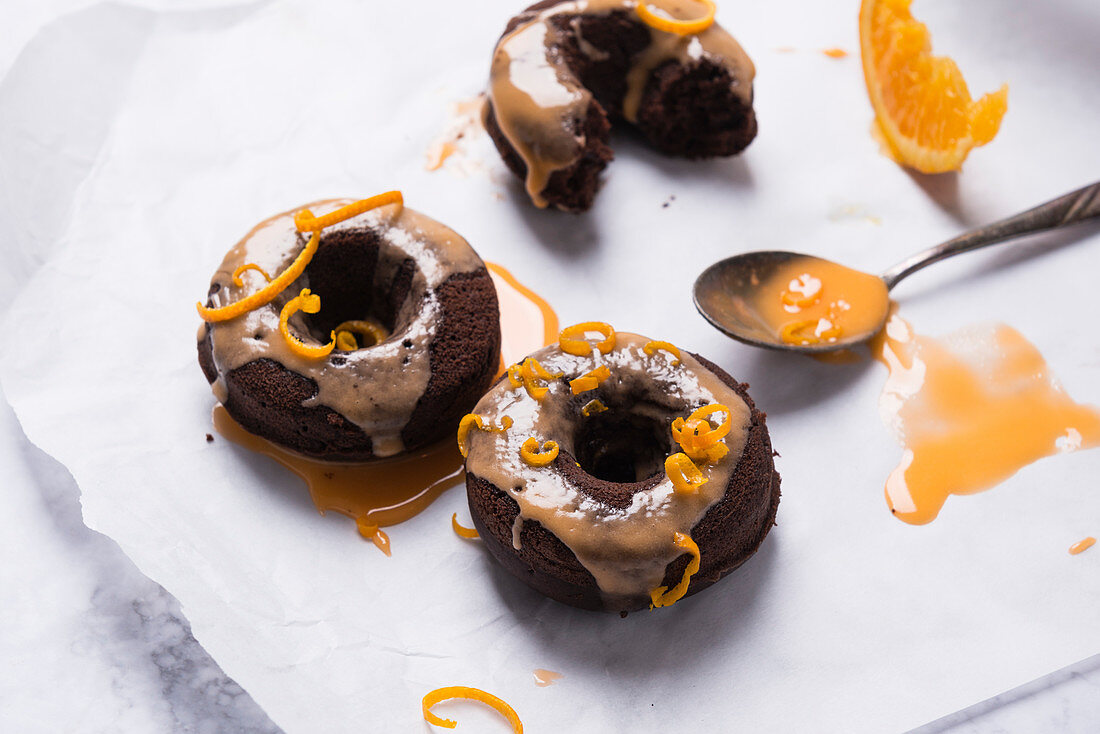 Vegan oven-baked chocolate donuts with orange icing and orange zest
