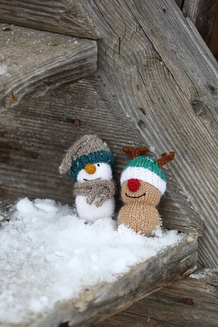 Knitted winter decorations in shapes of snowman and reindeer on rustic wood