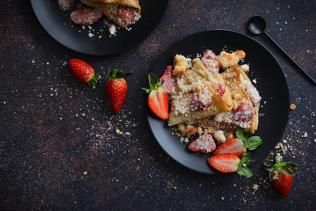 Pancakes mit Erdbeeren auf schwarzem Teller