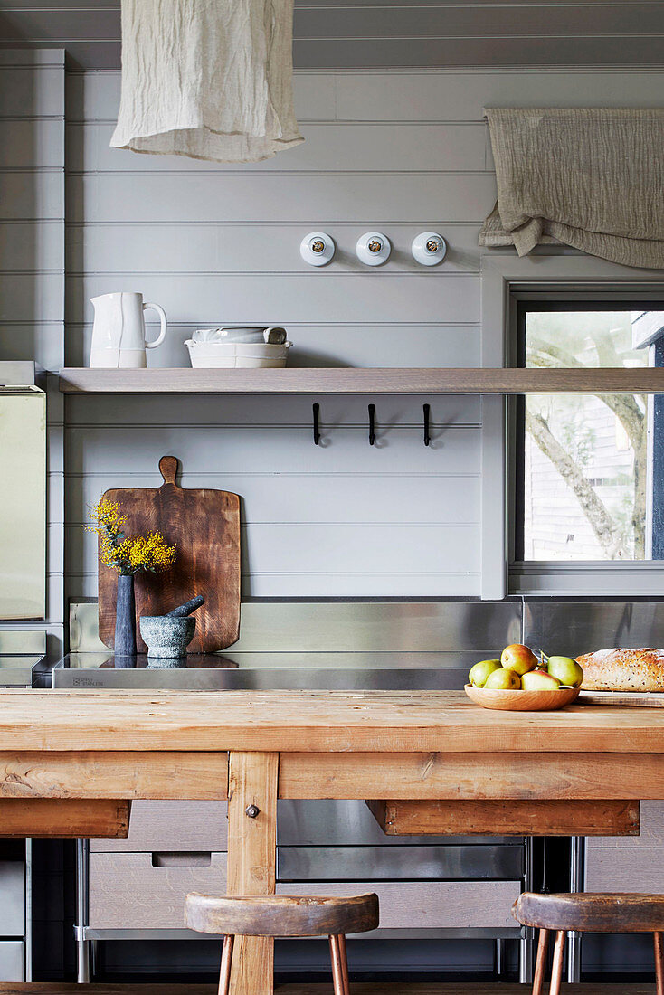 Blick über Esstisch aus Holz auf Küchenregal