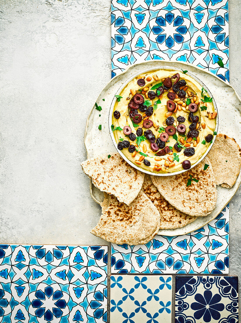 Warm hummus with pine nuts, raisins and olives