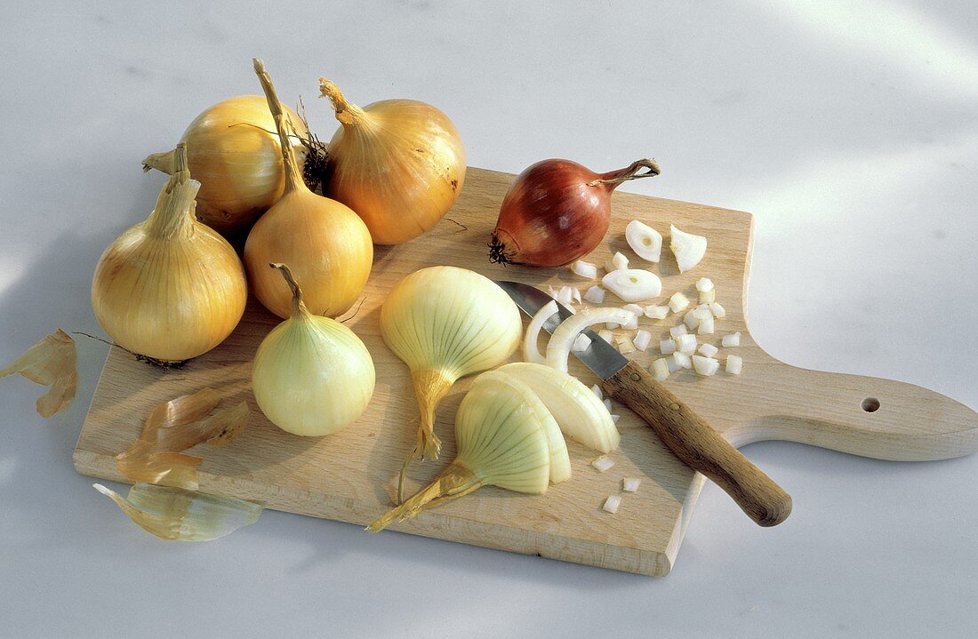 Zwiebeln, zum Teil geschält & geschnitten auf Holzbrett