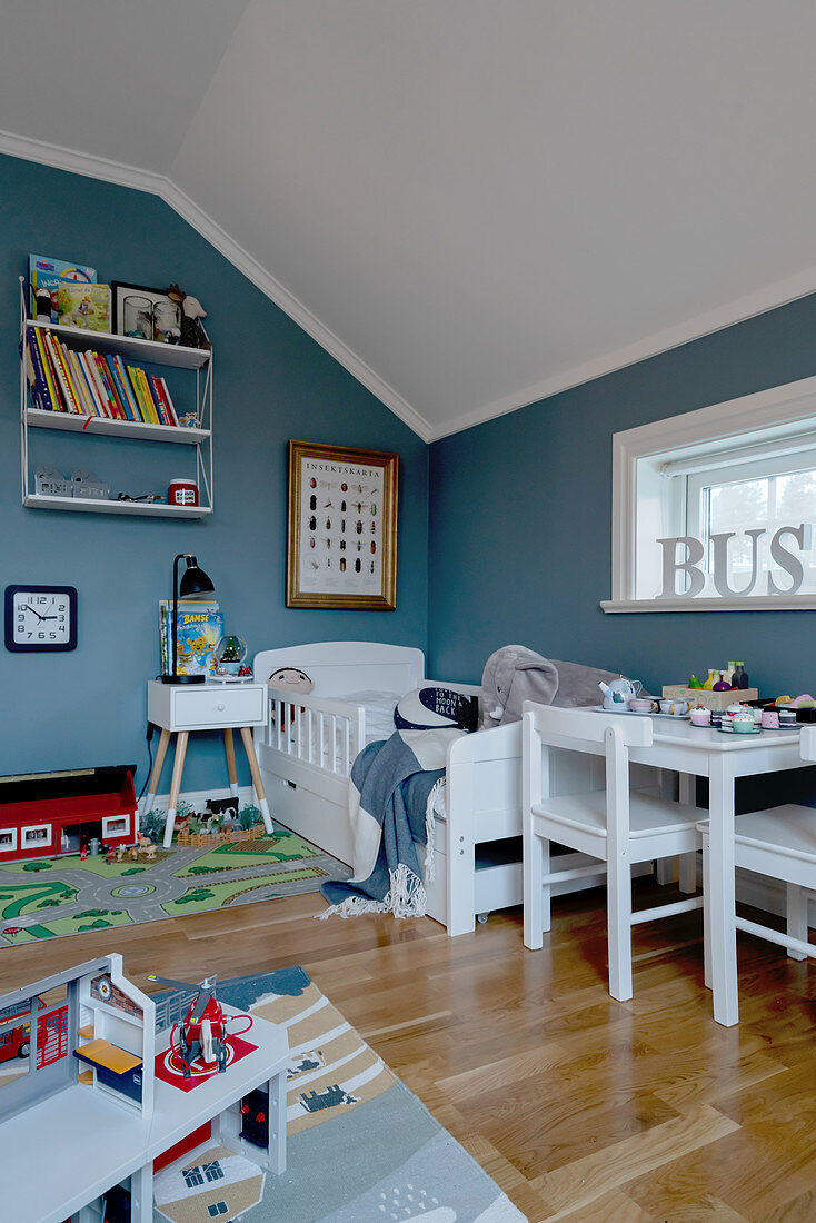 White furniture in child's bedroom with blue walls and sloping ceiling