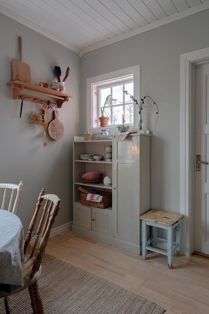 Old cabinet against grey wall in simple kitchen-dining room