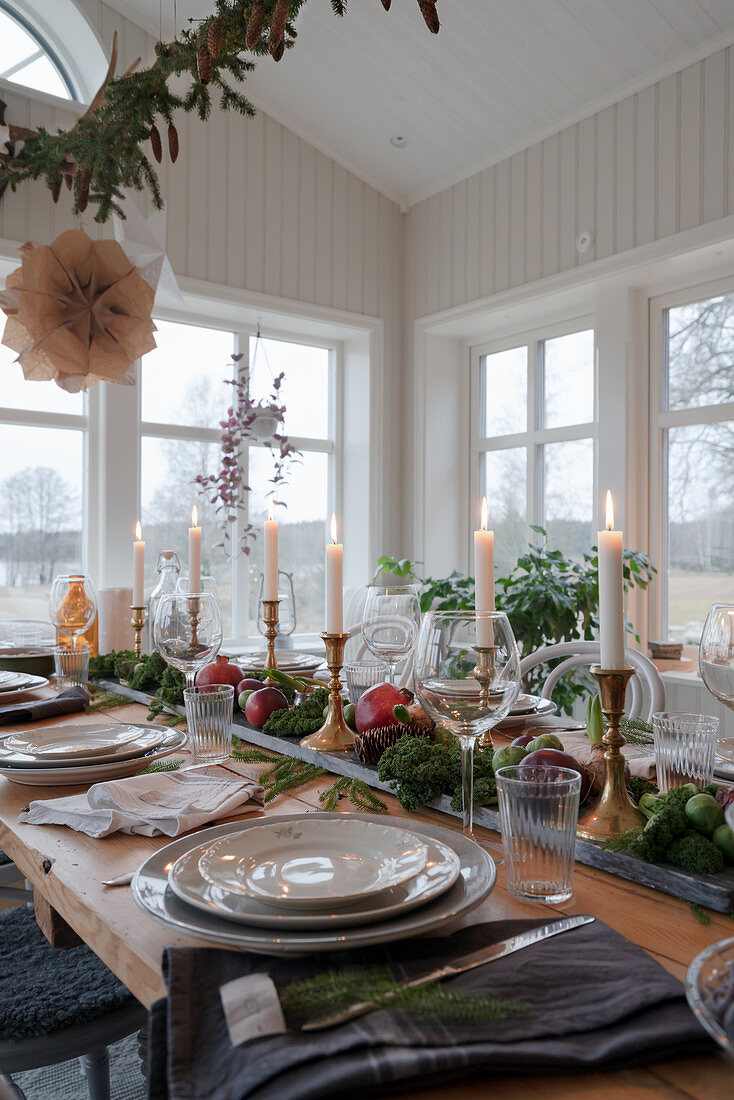 Centrepiece of candles, pomegranates and vegetables on set dining table