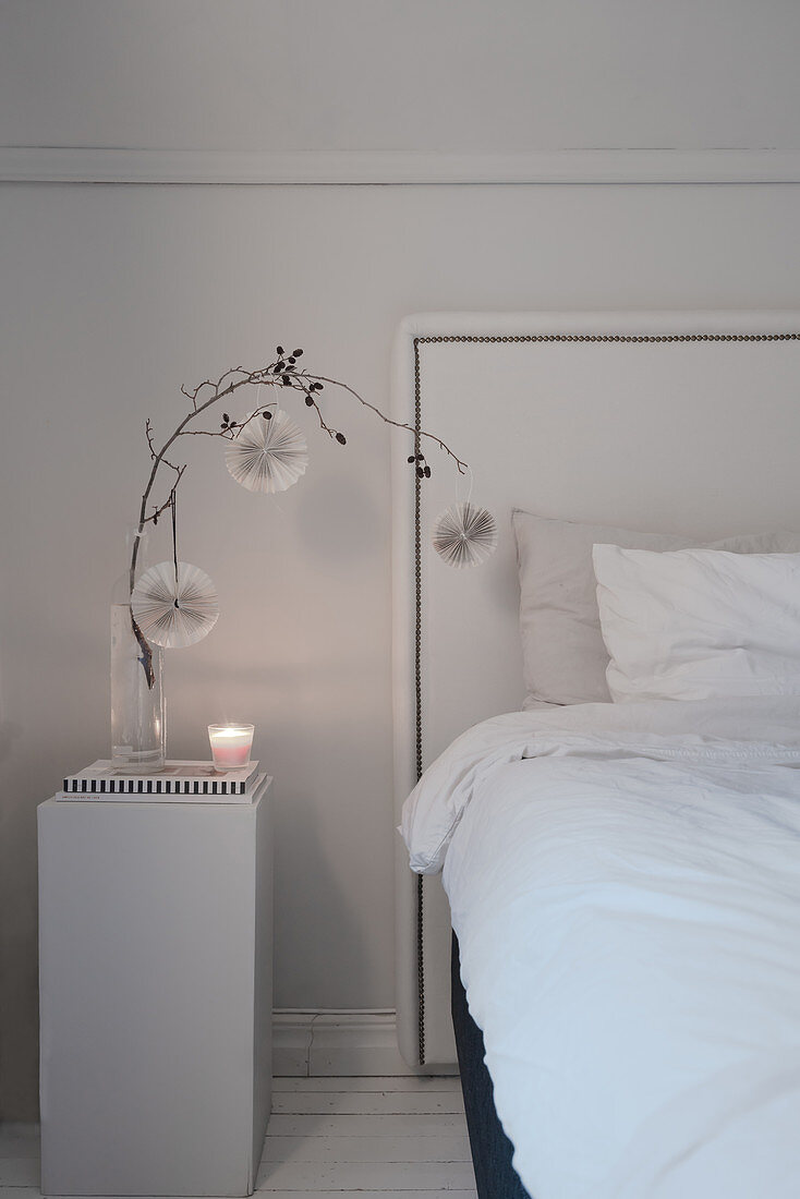 Branch of paper rosettes on plinth used as bedside table