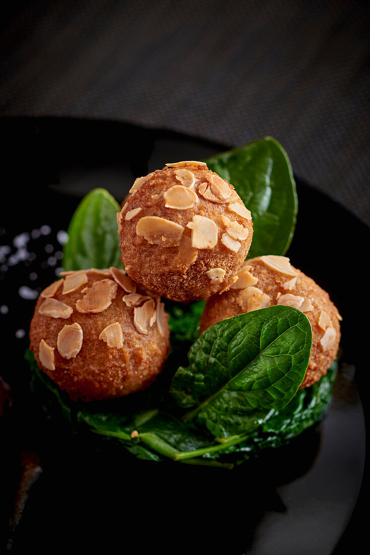 Potato croquettes with flaked almonds on spinach