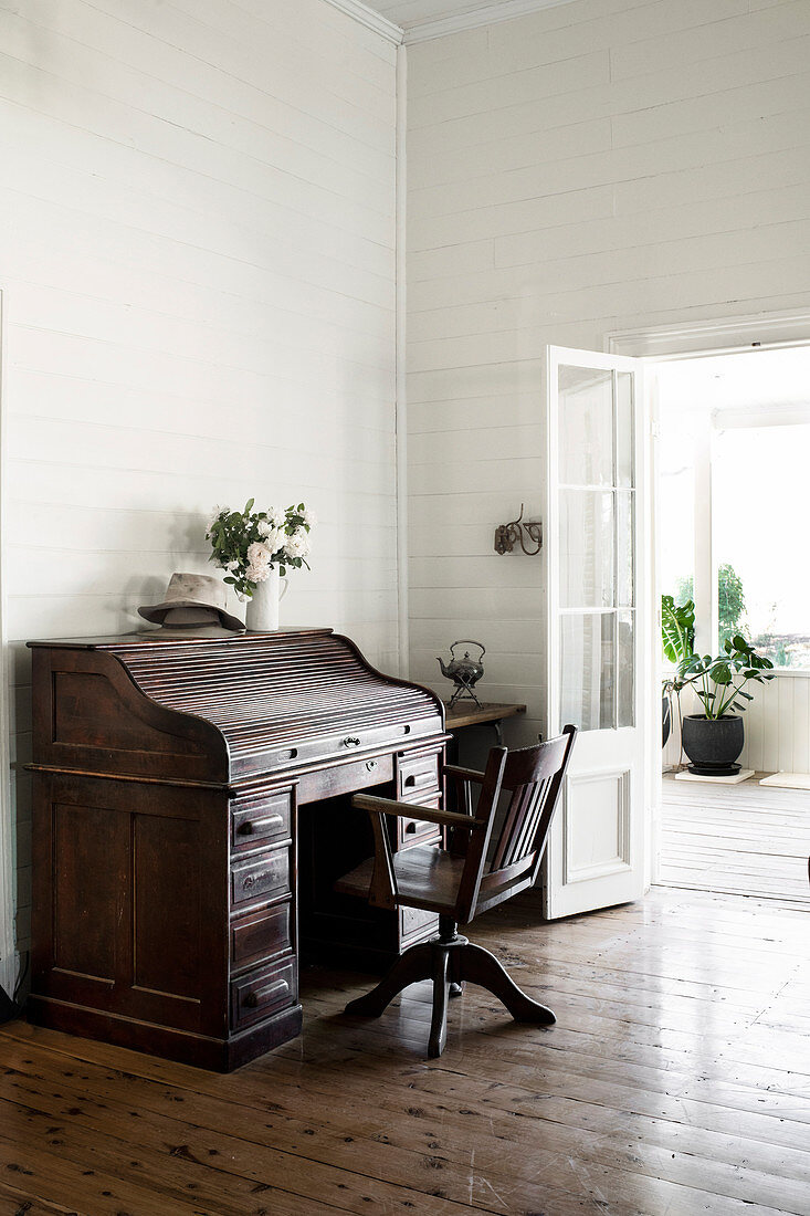 Old secretary and swivel chair on plank floor in high room