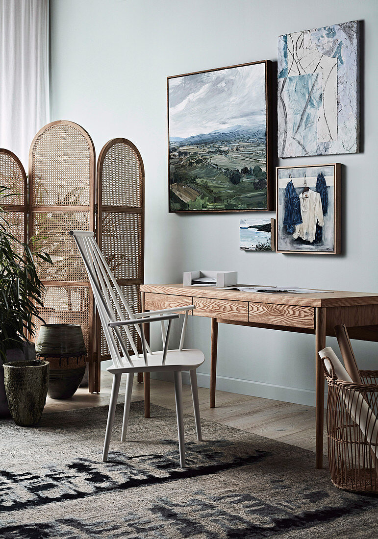 Barred chair at the wooden table in front of a light blue wall with pictures