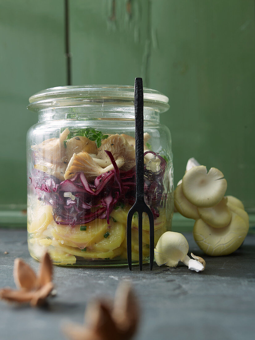 Layered salad with mushrooms, red cabbage and potatoes in a glass jar