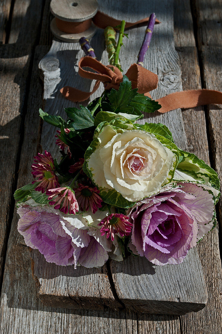 Herbstlicher Strauß aus Zierkohl und Chrysanthemen mit brauner Schleife