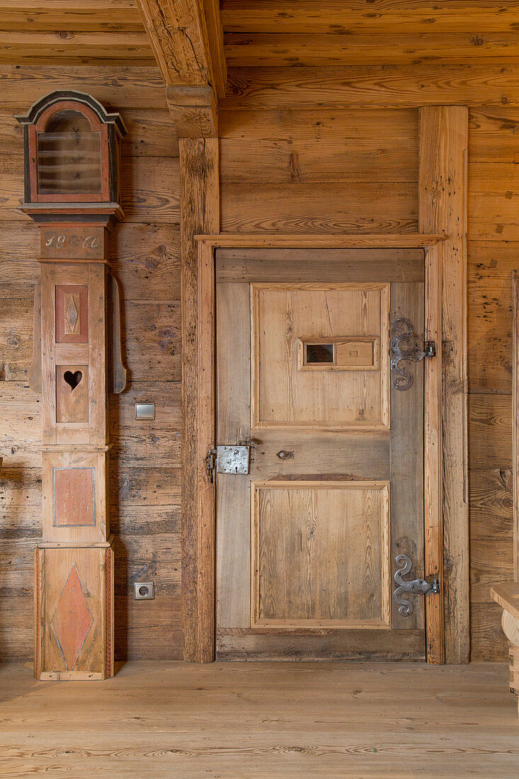 Antike Standuhr neben der Kassettentür in rustikaler Bauernstube