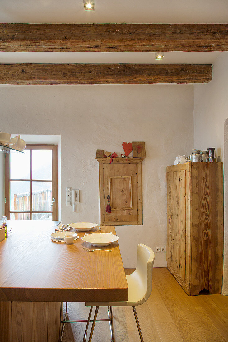 Modern wooden table in rustic parlour with old wooden ceiling beams