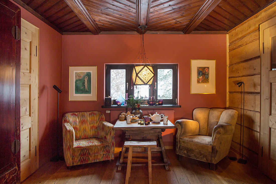 Armchairs at set table in front of red wall in rustic dining room