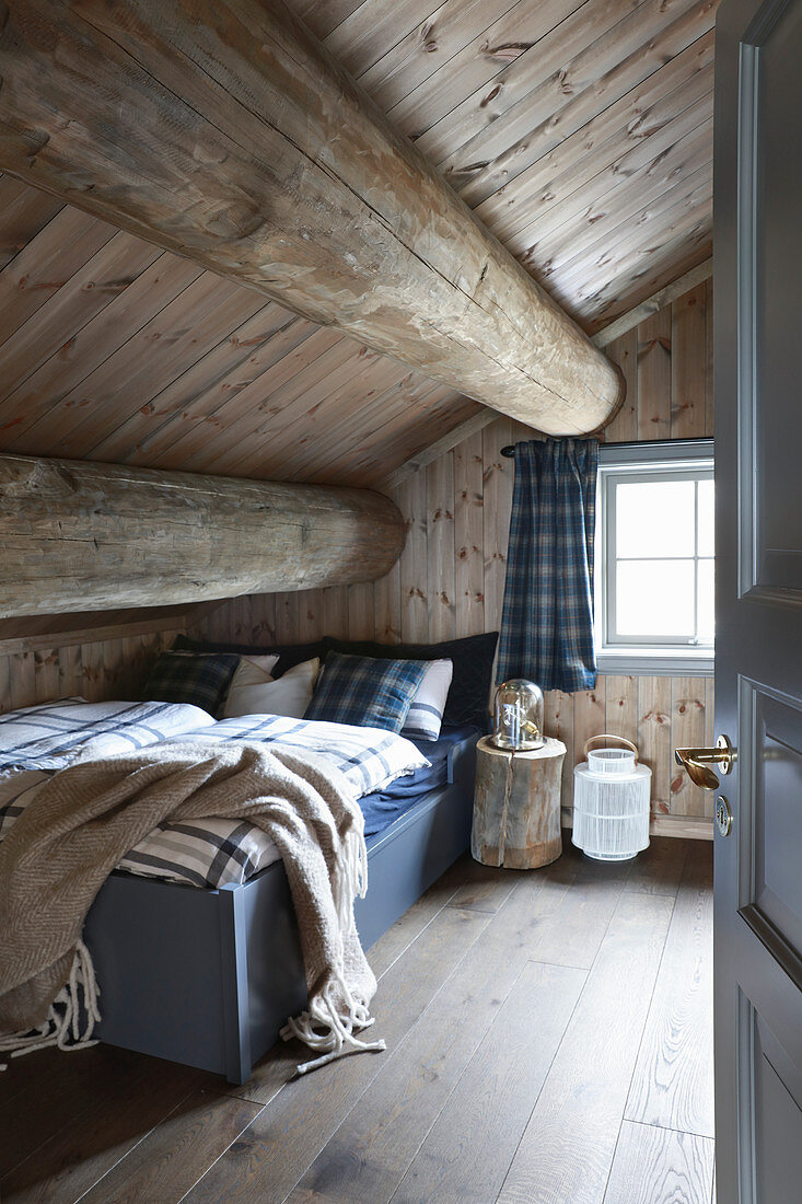 Rustikales Schlafzimmer unter der Dachschräge im Blockhaus