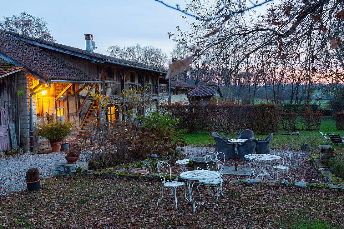 Gartenmöbel im abendlichen Herbst-Garten vorm Fachwerkhaus