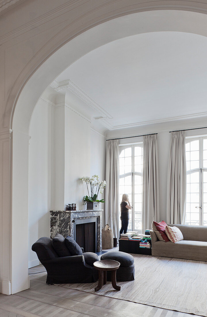 View of armchair and fireplace in living room seen through arched open doorway