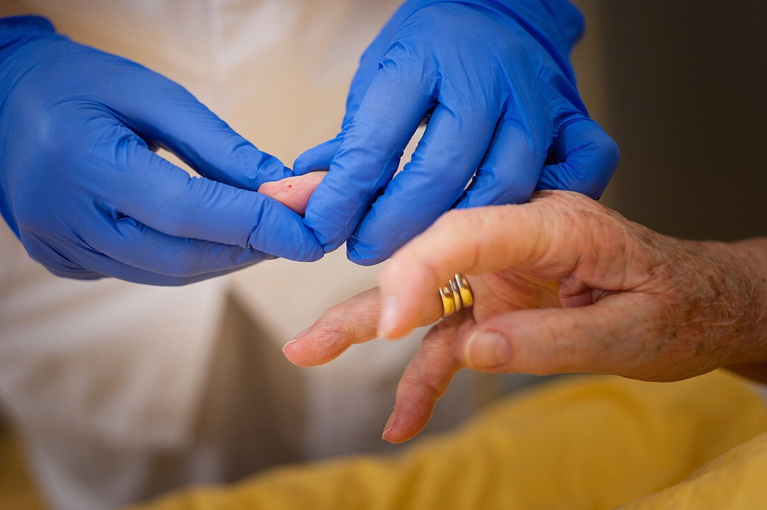 Nurse taking a finger prick blood sample