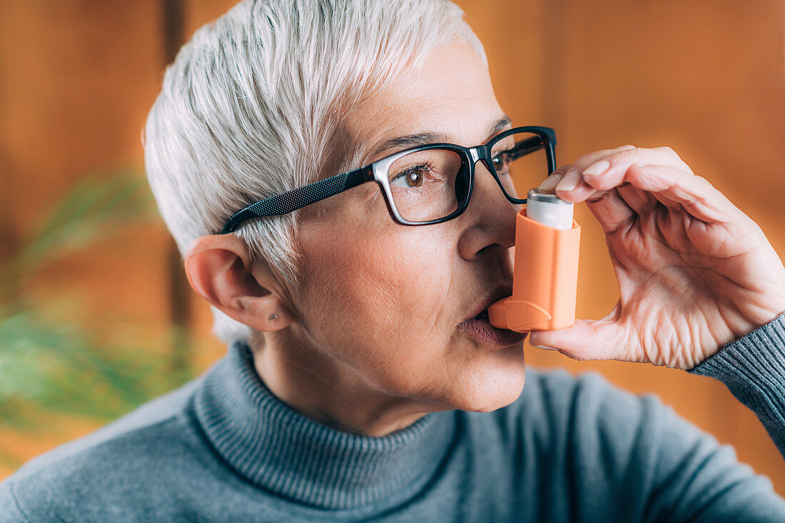 Senior woman inhaling medicine from asthma pump