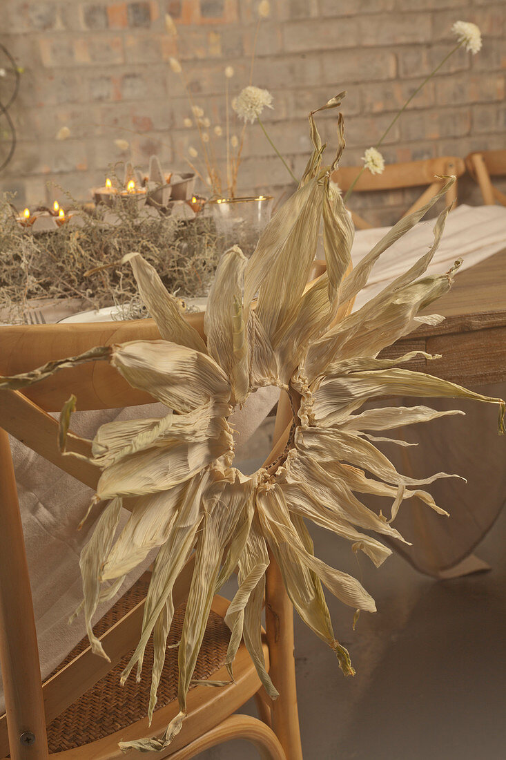 Wreath of maize leaves on chair at rustically set table