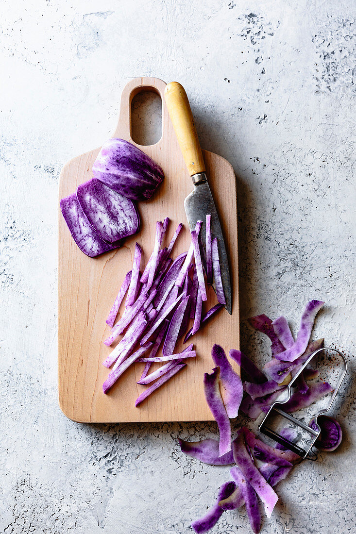 Lila Daikon in Julienne-Streifen auf Holzschneidebrett