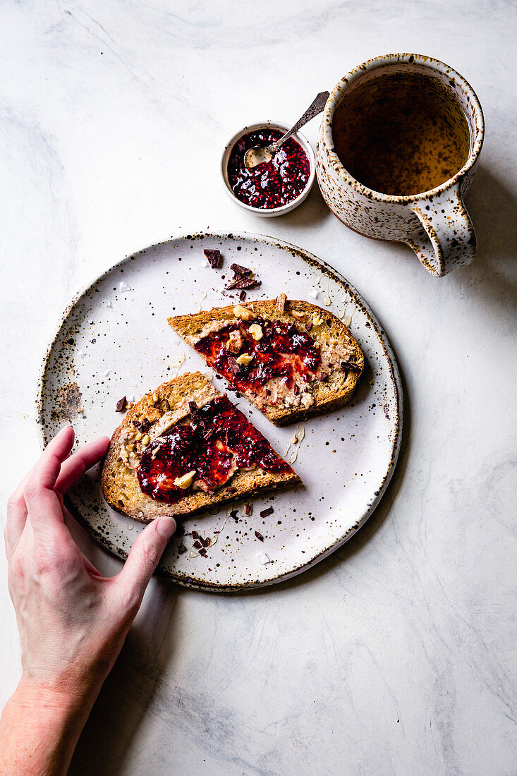Toast with nut butter and jam on a plate with a cup of tea.