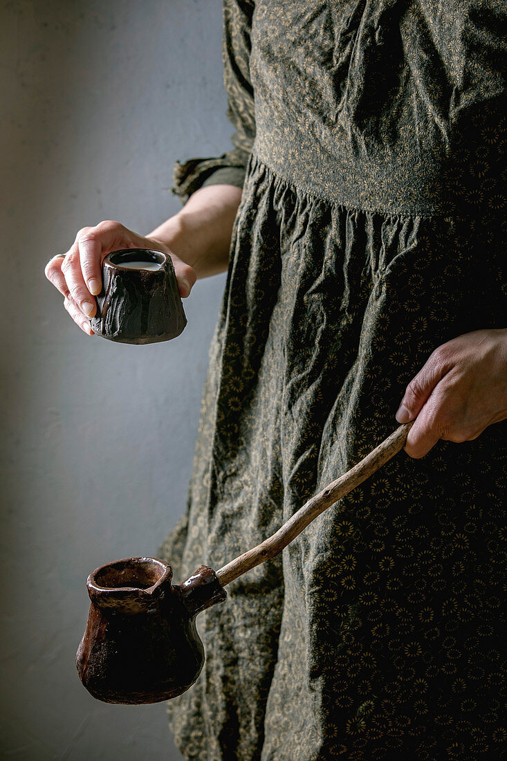Frau hält Milchkännchen und Cezve für türkischen Kaffee in den Händen