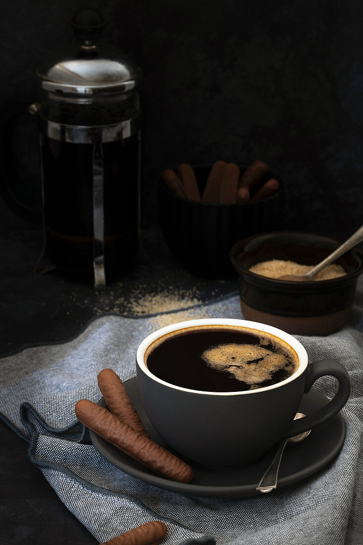 Eine Tasse schwarzer Kaffee serviert mit Schokoladengebäck