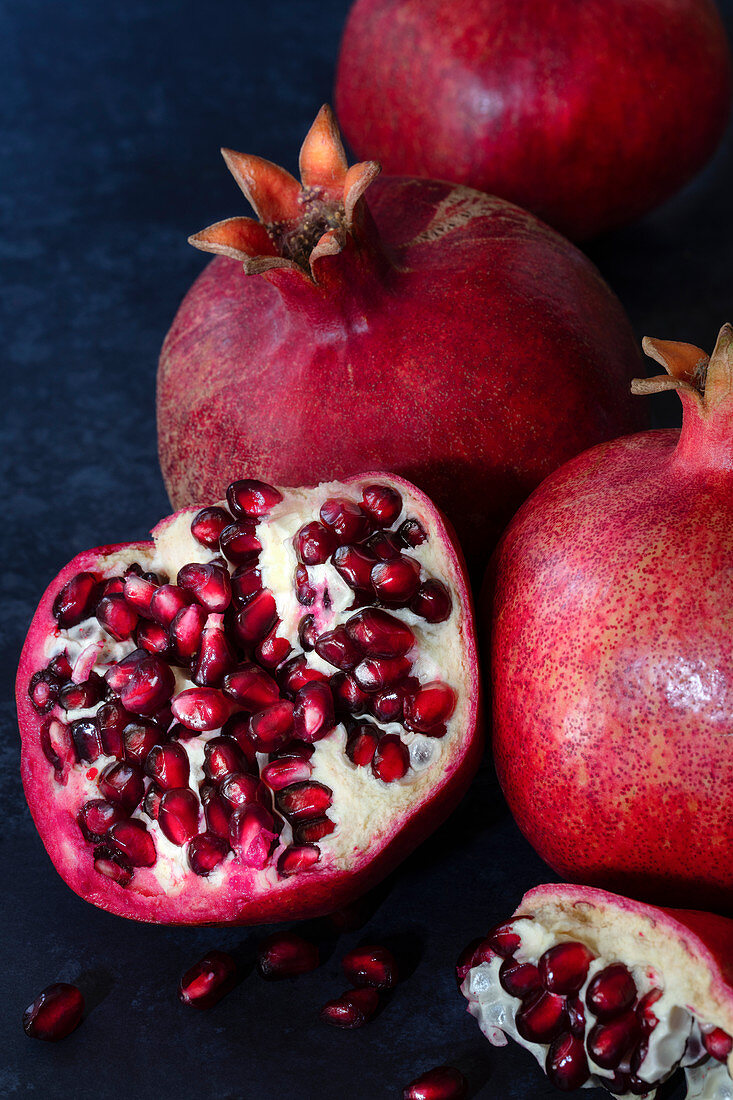 Red, ripe, juicy pomegranates against a dark blue background.