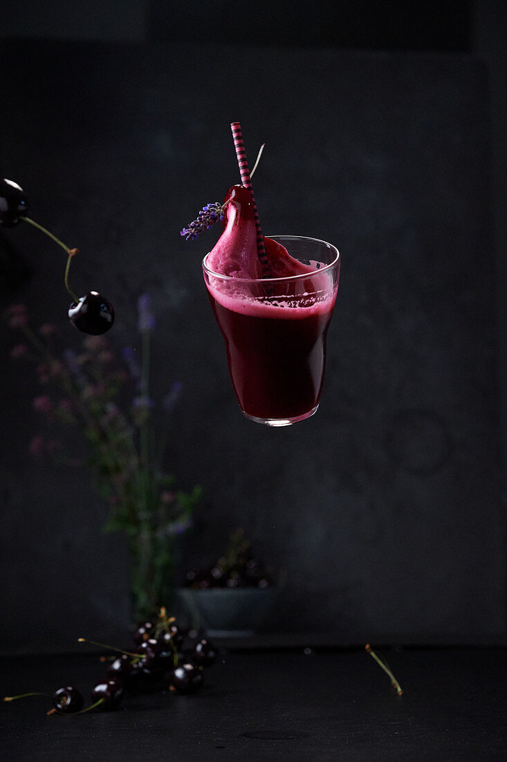 Ein schwebendes Glas Gin Sour mit Rote-Bete und Kirschen